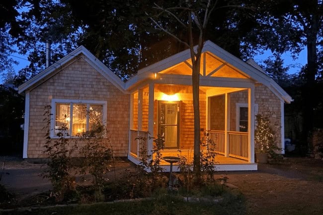 Cozy illuminated exterior of a residential home featuring a porch, showcasing quality carpentry and design, relevant to Coast Carpentry's deck building and home improvement services in Cape Cod, MA.