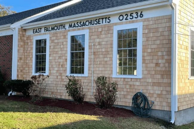 East Falmouth, Massachusetts building exterior with shingle siding, large windows, and address displayed prominently.