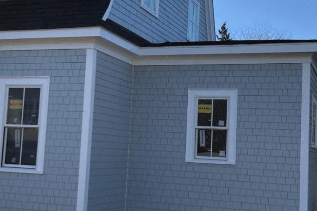 Newly constructed gray shingle house exterior with white trim and windows, showcasing Coast Carpentry's home improvement services.