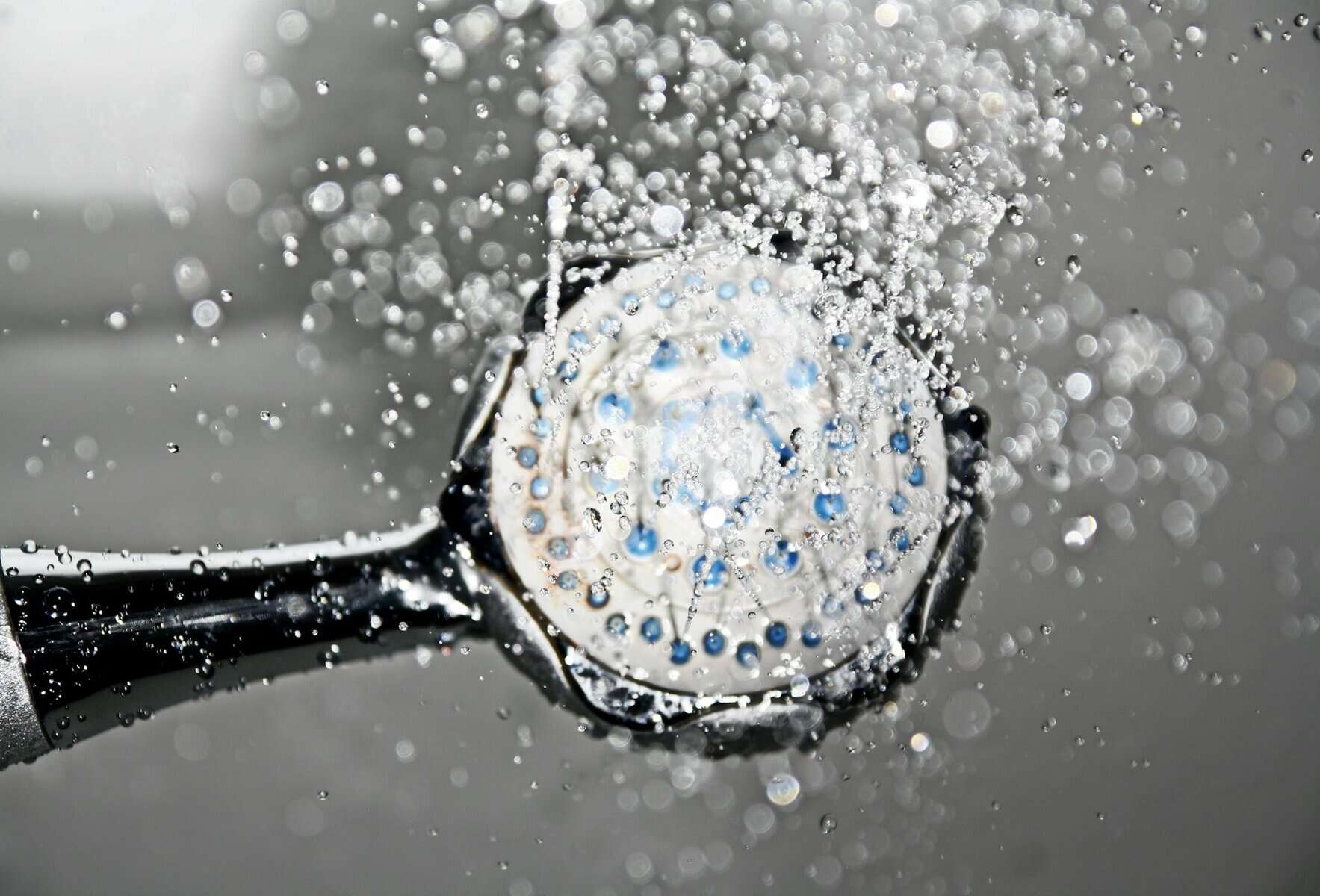 Showerhead spraying water, illustrating solutions for improving water pressure in home showers.