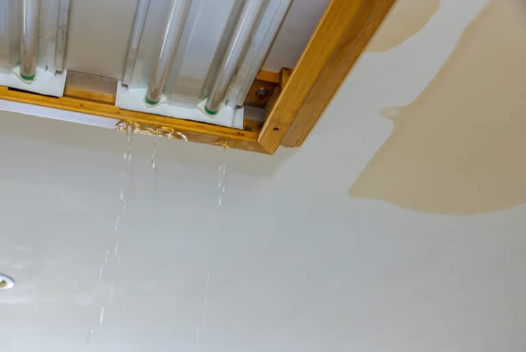 Water leaking from ceiling with visible stains, indicating potential roof damage, relevant to Cape Cod homeowners addressing seasonal roof maintenance issues.