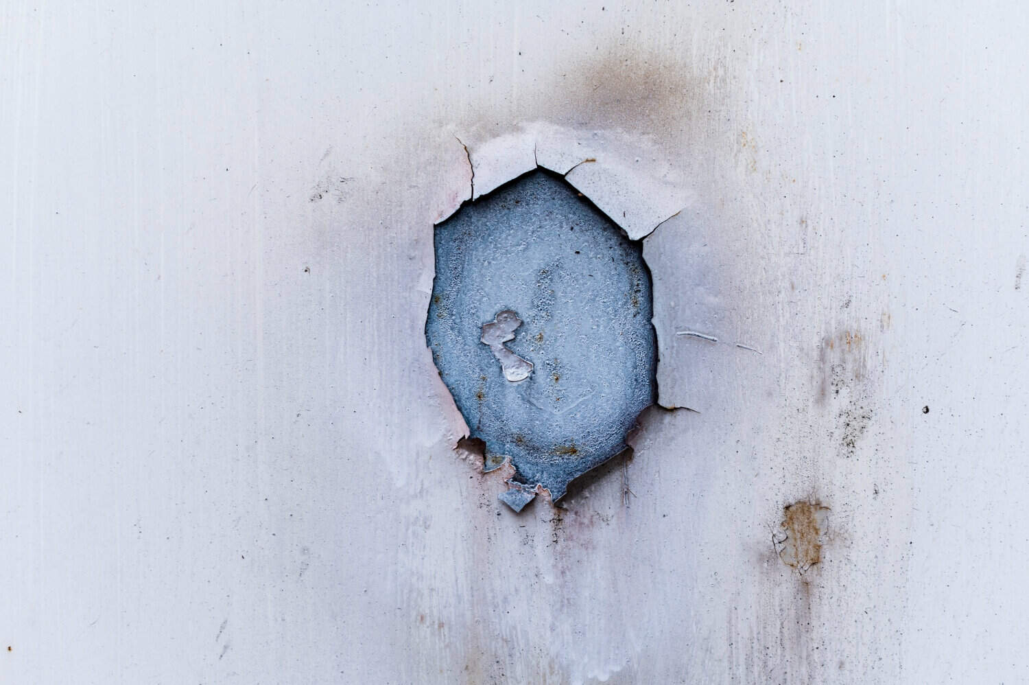 Peeling paint revealing a blue surface underneath, indicative of water damage, relevant to masonry and home repair discussions in Cape Cod.