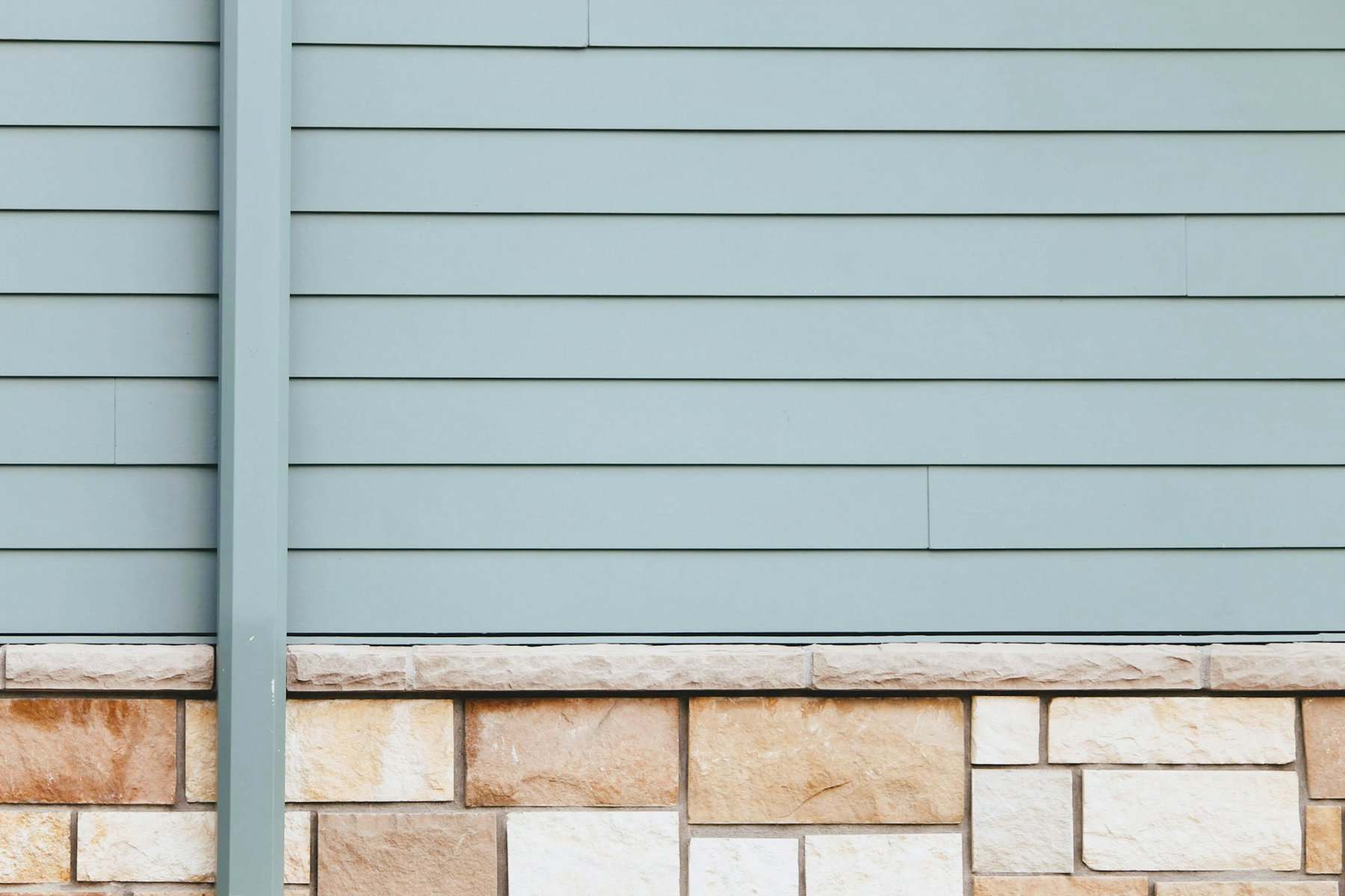 Siding and stone foundation of a residential building, illustrating construction materials relevant to home improvement and maintenance topics.