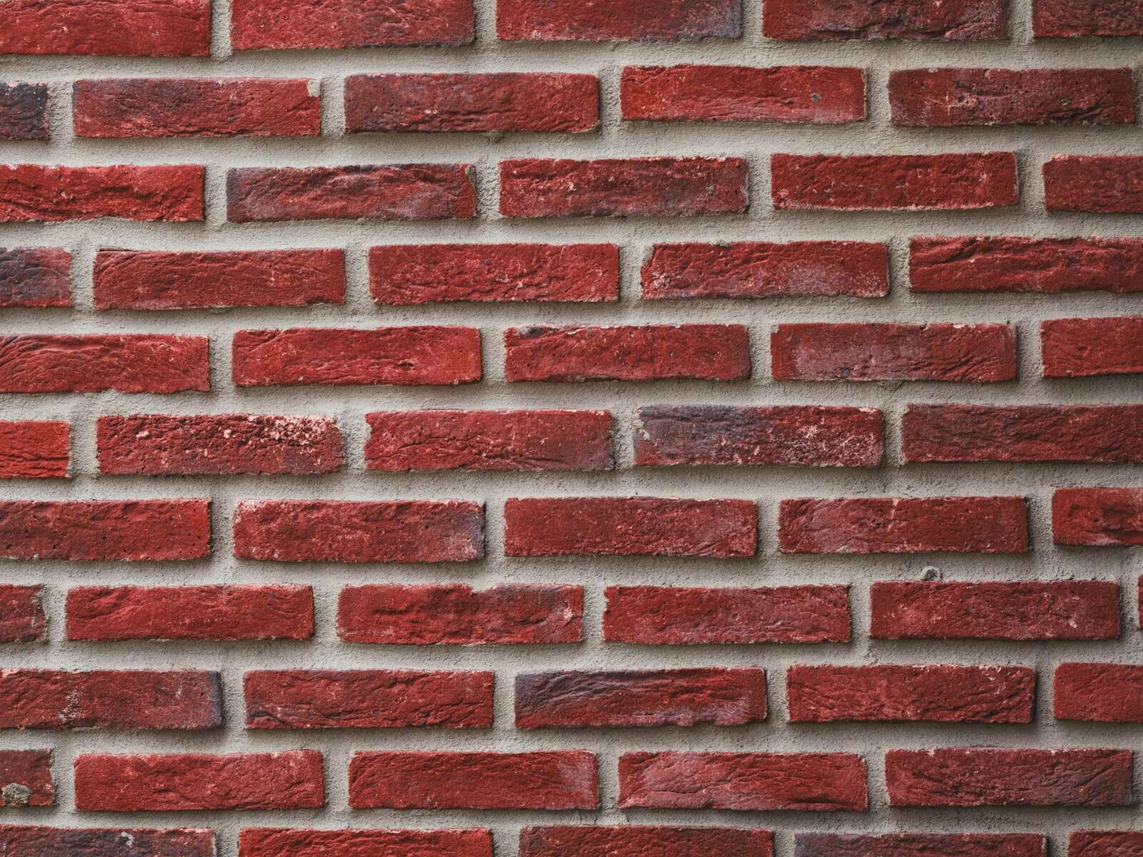 Red brick wall texture with mortar joints, relevant to construction and repair topics.