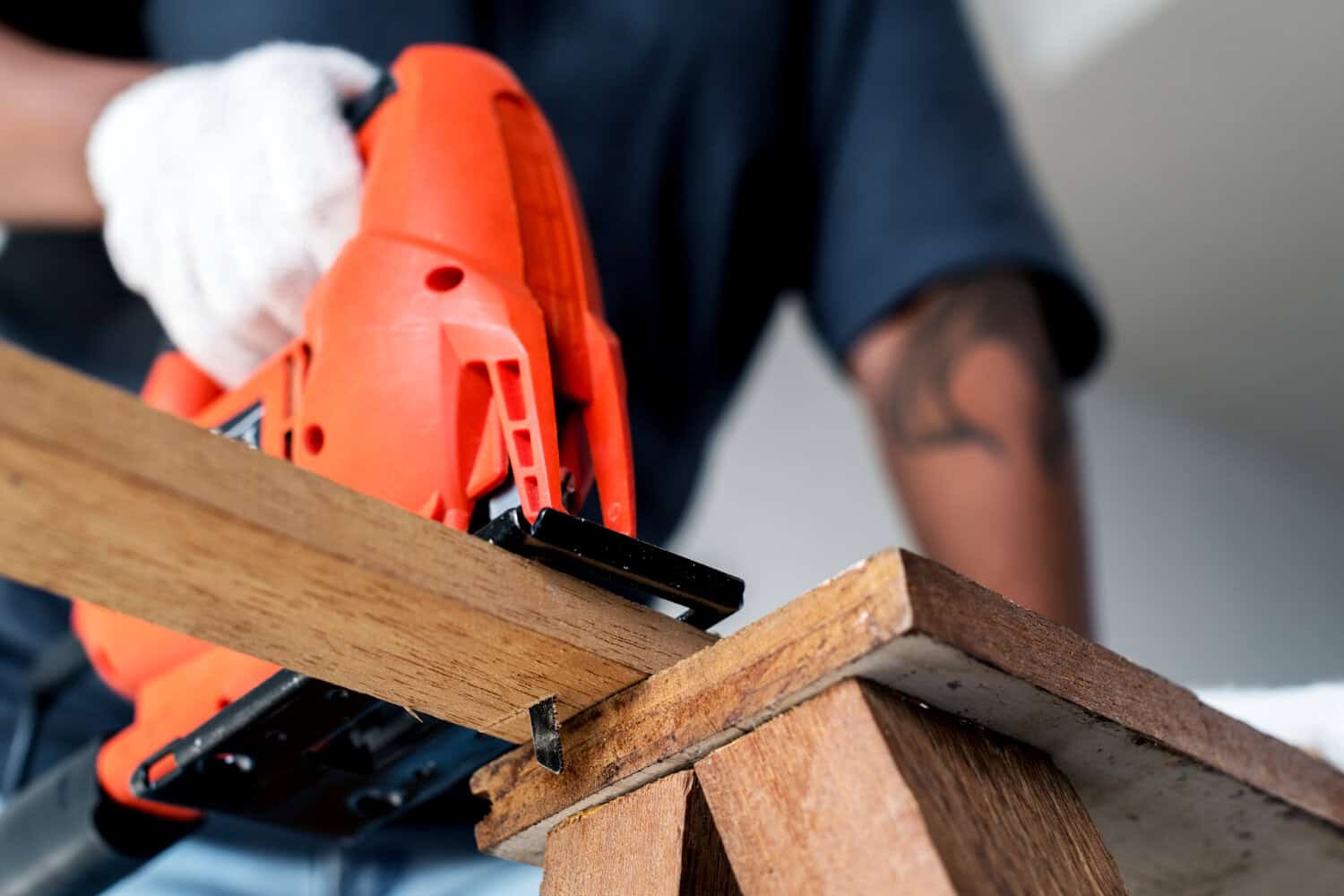 Person using a jigsaw on a wooden board, demonstrating carpentry skills relevant to construction and remodeling in Cape Cod homes.