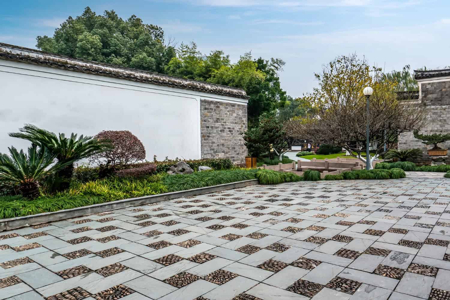 Front yard masonry featuring patterned stone paving, lush greenery, and decorative landscaping, highlighting Cape Cod's outdoor aesthetics.