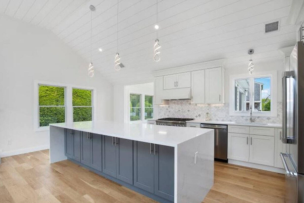 Finished Coast Carpentry kitchen on Cape Cod with a long gray shaker island and white perimeter cabinets